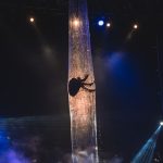 Aerial performer gracefully suspended on stage with dramatic lighting effects at night.