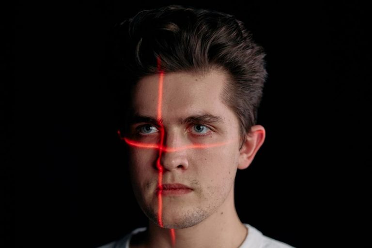 Conceptual portrait with laser scanning for facial recognition on plain black background.