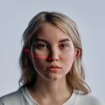 Biometric Surveillance in the Workplace: Risks to Productivity Close-up of a young woman with facial recognition lasers projected, symbolizing future technology.