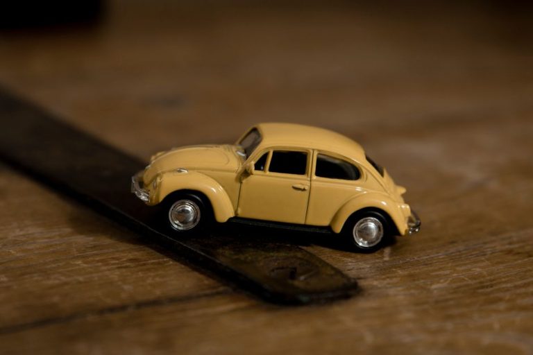 Close-up shot of a yellow toy Volkswagen Beetle on a wooden background, emphasizing detail and design.