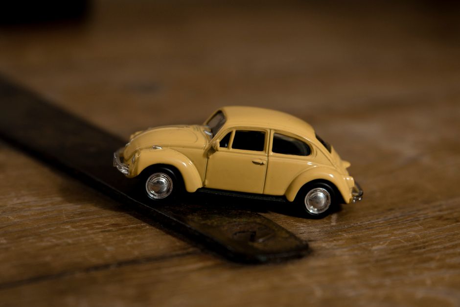 Close-up shot of a yellow toy Volkswagen Beetle on a wooden background, emphasizing detail and design.