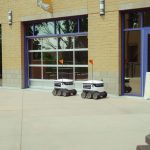 Two autonomous delivery robots navigate an outdoor space, showcasing modern technology and innovation.