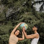 A diverse couple holding a globe outdoors, symbolizing environmental connection and global unity.