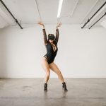Building High-Performance Virtual Communities: Strategic Guide A woman wearing a black leotard and VR headset performs a dance pose indoors.