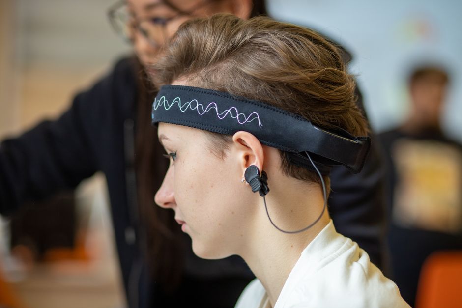 Close-up of a young woman wearing an EEG headband, showcasing modern technology indoors.