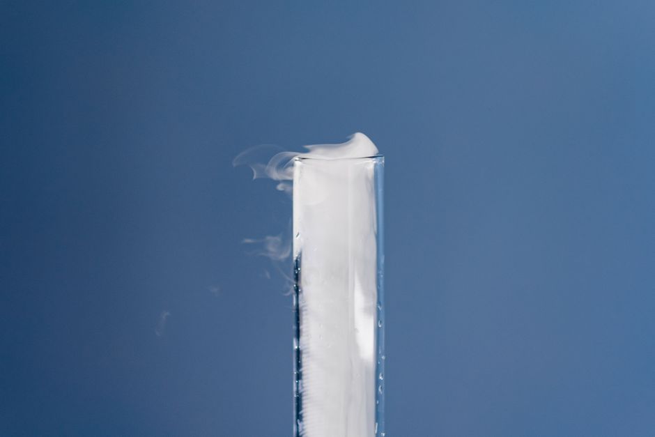 A scientific experiment with a test tube emitting vapor, set against a calming blue background.