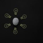Conceptual photo of a brain surrounded by light bulb clips on black background.