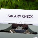 Compensation Models: Aligning Pay with High-Performance Strategy Close-up of a vintage typewriter typing 'Salary Check' on paper, symbolizing payroll and finance.