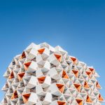 A stunning geometric architectural design against a vibrant blue sky in Dubai.