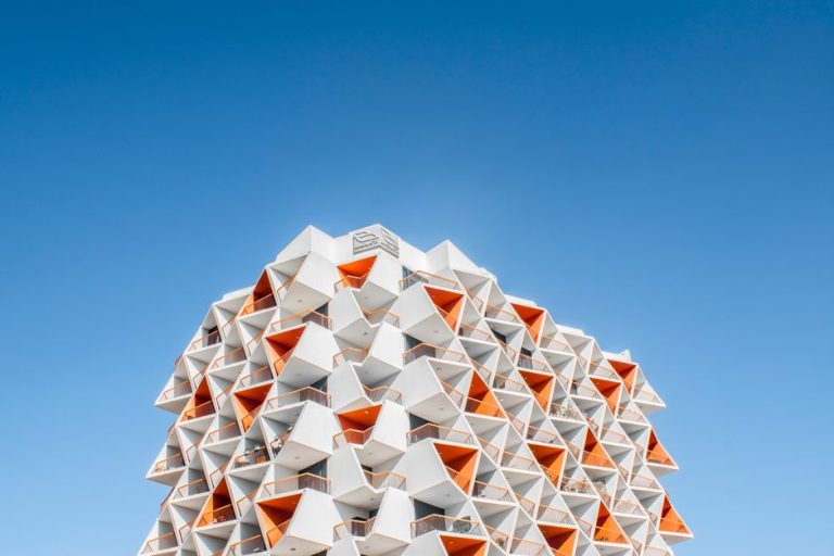 A stunning geometric architectural design against a vibrant blue sky in Dubai.