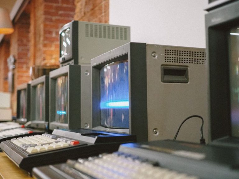 Row of vintage CRT computer monitors showcasing classic technology indoors.