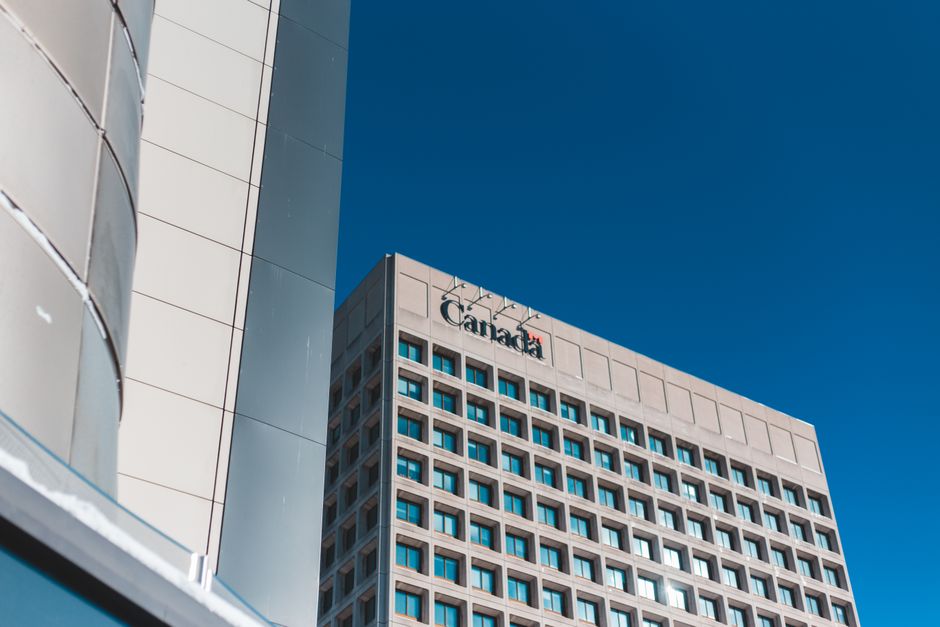 Low angle view of a modern skyscraper in Canada against a clear blue sky.