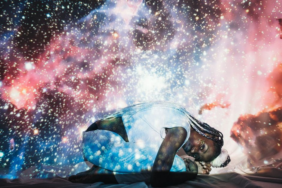Artistic double exposure of a woman with a cosmic galaxy background, creating a dreamy and ethereal effect.