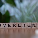 Wooden Scrabble tiles spelling out 'Sovereignty' on a blurred natural background.