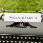Vintage typewriter outdoors with 'Decentralized' typed paper, symbolizing old meets new in technology.