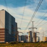 Cityscape featuring tall apartment buildings and electricity towers under a clear sky.