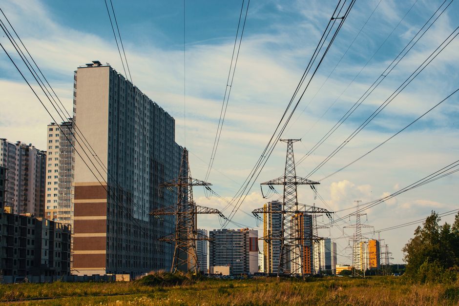 Cityscape featuring tall apartment buildings and electricity towers under a clear sky.