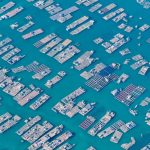 Aerial photo capturing extensive fish farms with grid-like structures in deep blue waters.