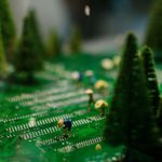 Creative scene of miniature figures farming on a circuit board with artificial trees.