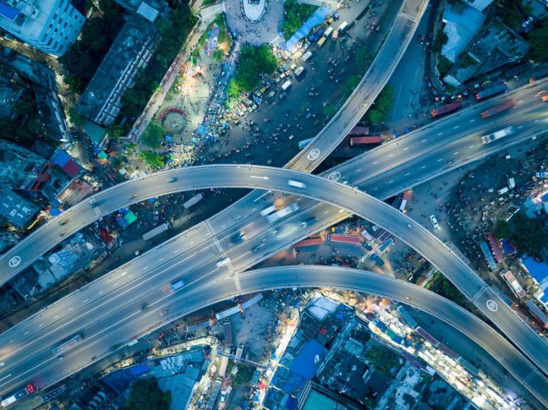 Dynamic aerial shot of a bustling city highway intersection at night.