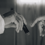 Close up view of two hands exchanging a USB drive against a blurred background.