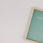 A minimalist photo of a wooden frame displaying the word 'Vote' on a green background, ideal for election themes.