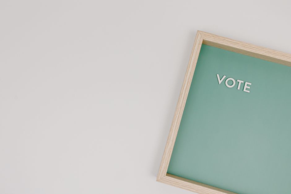 A minimalist photo of a wooden frame displaying the word 'Vote' on a green background, ideal for election themes.