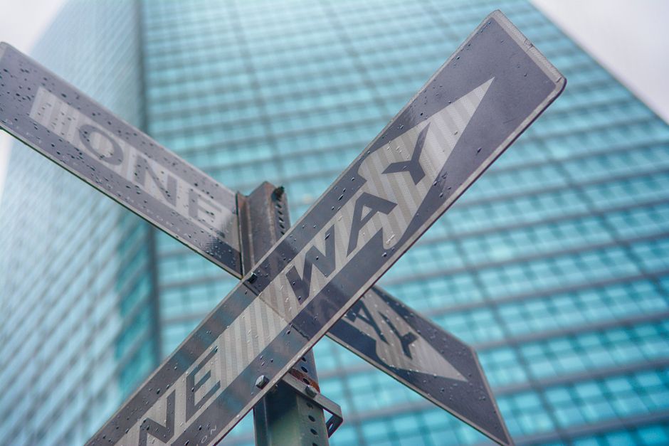 Close-up of a one way street sign in front of a skyscraper in New York City.