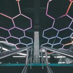 Explore a modern subway station with a futuristic design featuring illuminated geometric patterns and stainless steel railings.