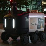 Drone Delivery Strategy: Scaling Logistics & Operational Edge Close-up view of an autonomous delivery robot on a city street at night under artificial light.