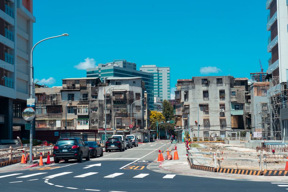 A vibrant urban street with cars, construction, and classic city buildings under a clear blue sky.