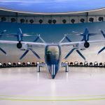 Electric Aviation Strategy: Operational Efficiency & Trends Front view of a futuristic electric vehicle with propellers displayed indoors.