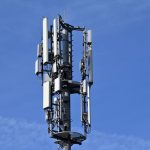 Electromagnetic Shielding 80: Secure Your Physical Infrastructure A modern cell tower with antennas against a clear blue sky, symbolizing connectivity.