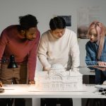 Elite Formation: Architecting High-Performance Organizational Systems A diverse group of professionals discussing an architectural model in an office setting, emphasizing teamwork.