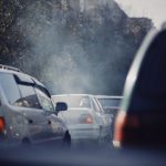 City traffic jam with cars emitting smoke on a busy road.