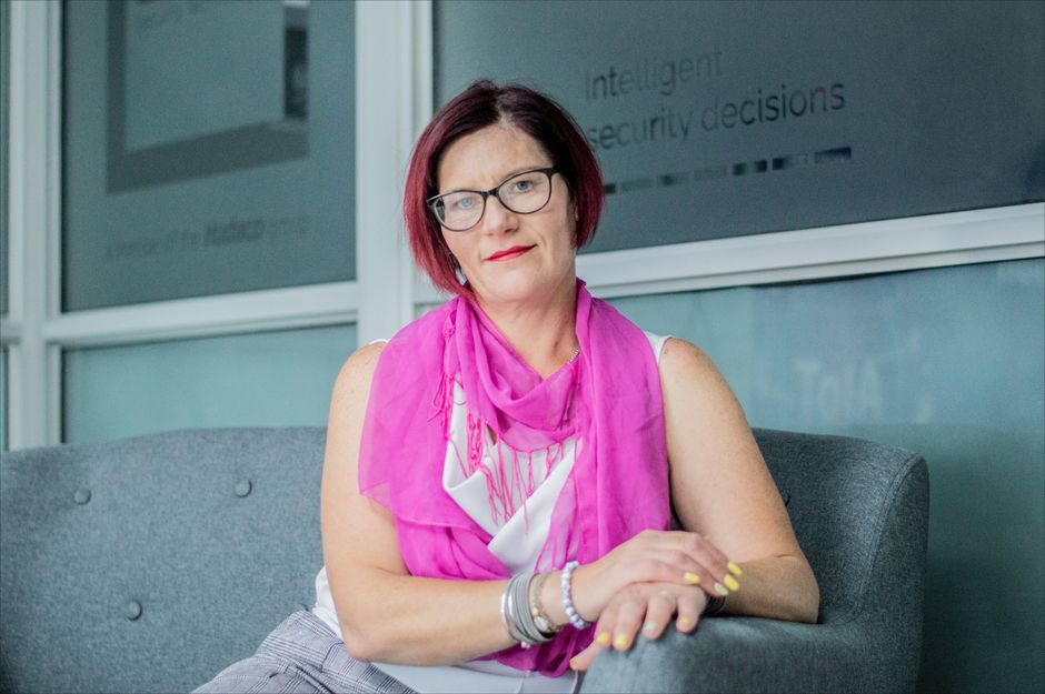 Portrait of a confident woman sitting indoors wearing glasses and pink scarf.