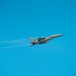 A military jet flies through a clear sky, showcasing agile aerial maneuverability.