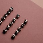 Close-up of beads spelling 'Strong Women Fight' on a brown background.