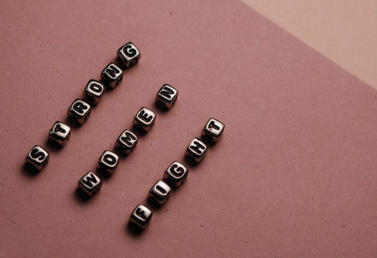 Close-up of beads spelling 'Strong Women Fight' on a brown background.