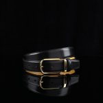 Sophisticated black leather belt featuring a sleek gold buckle, perfect for fashion-forward styling.