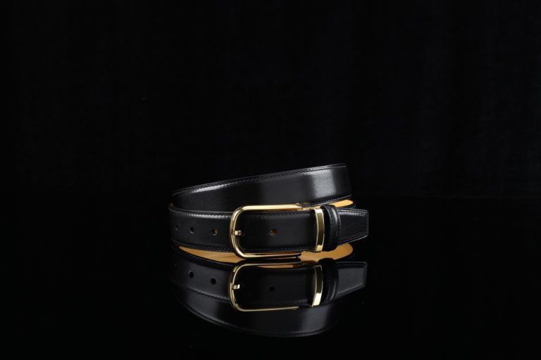 Sophisticated black leather belt featuring a sleek gold buckle, perfect for fashion-forward styling.