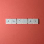 Close-up of the word 'SOCIAL' formed with tiles on a red surface, offering copyspace.