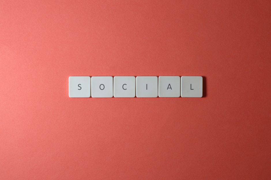 Close-up of the word 'SOCIAL' formed with tiles on a red surface, offering copyspace.