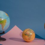 Three vividly colored globes displayed against a blue and pink backdrop, highlighting geography and education.