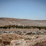 Geopolitical Resource Scarcity: Strategic Leadership for 2026 Expansive view of a refugee camp amidst a dry and rocky landscape in Idlib, Syria.
