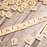 Wooden letter tiles forming the word 'inflation' on a rustic wooden surface, symbolizing economic themes.