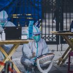 Global Health Surveillance: Predictive Strategy and Resilience Medical professionals in protective gear conducting outdoor COVID-19 testing operation.