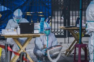 Medical professionals in protective gear conducting outdoor COVID-19 testing operation.