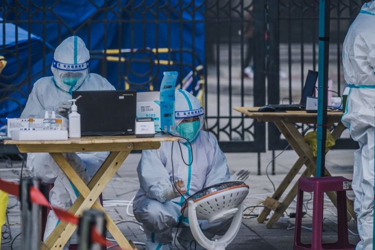 Medical professionals in protective gear conducting outdoor COVID-19 testing operation.