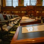 A detailed view of an empty legislative chamber with rows of desks and microphones, evoking governance.